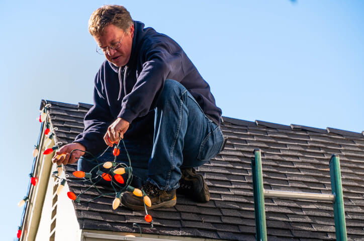 Man on roof adding christmas lights